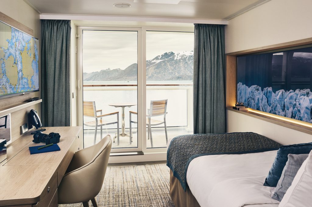 Single bed facing floor to ceiling windows in solo cabin on National Geographic Endurance & Resolution.