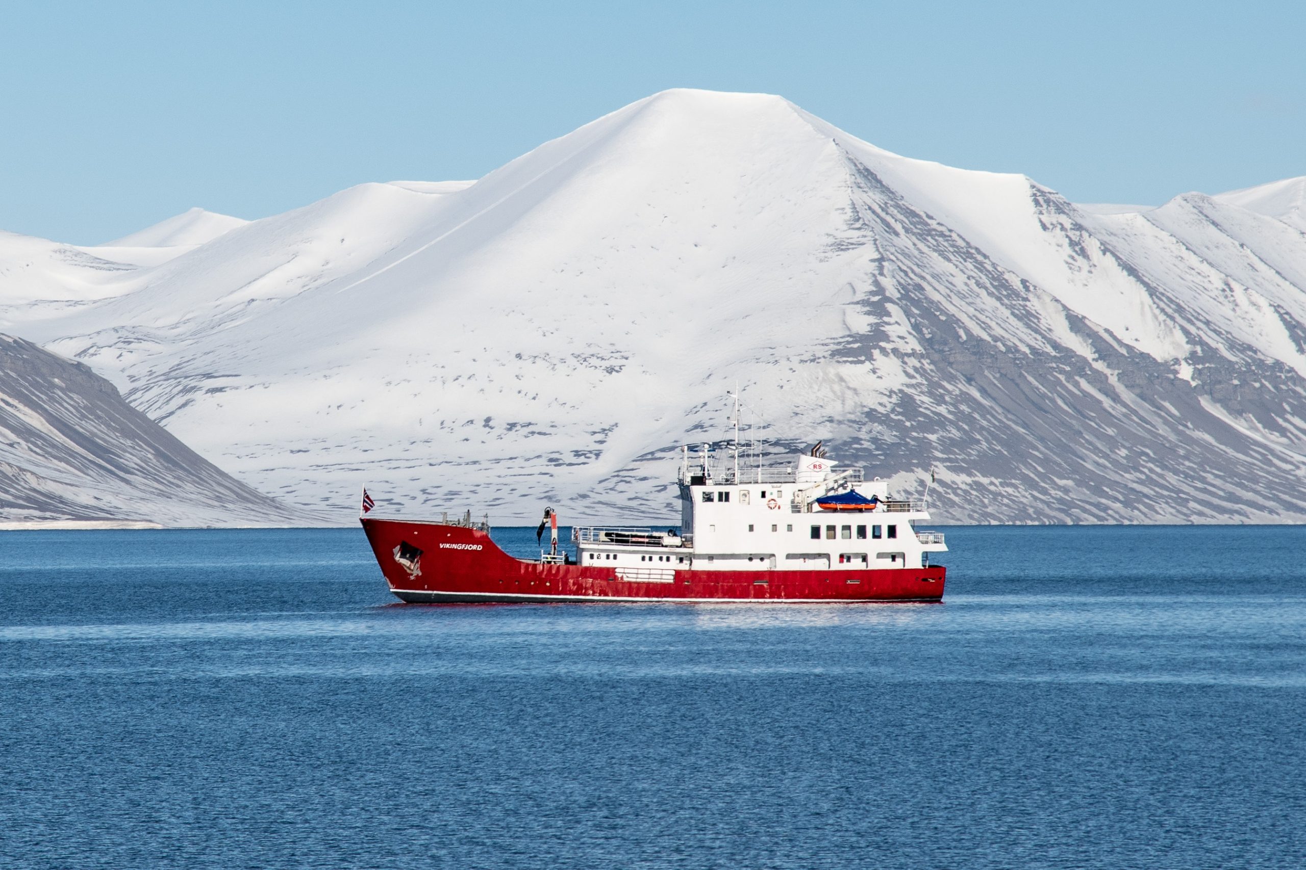 The ship Vikingfjord on the water with snowy mountain in background.
