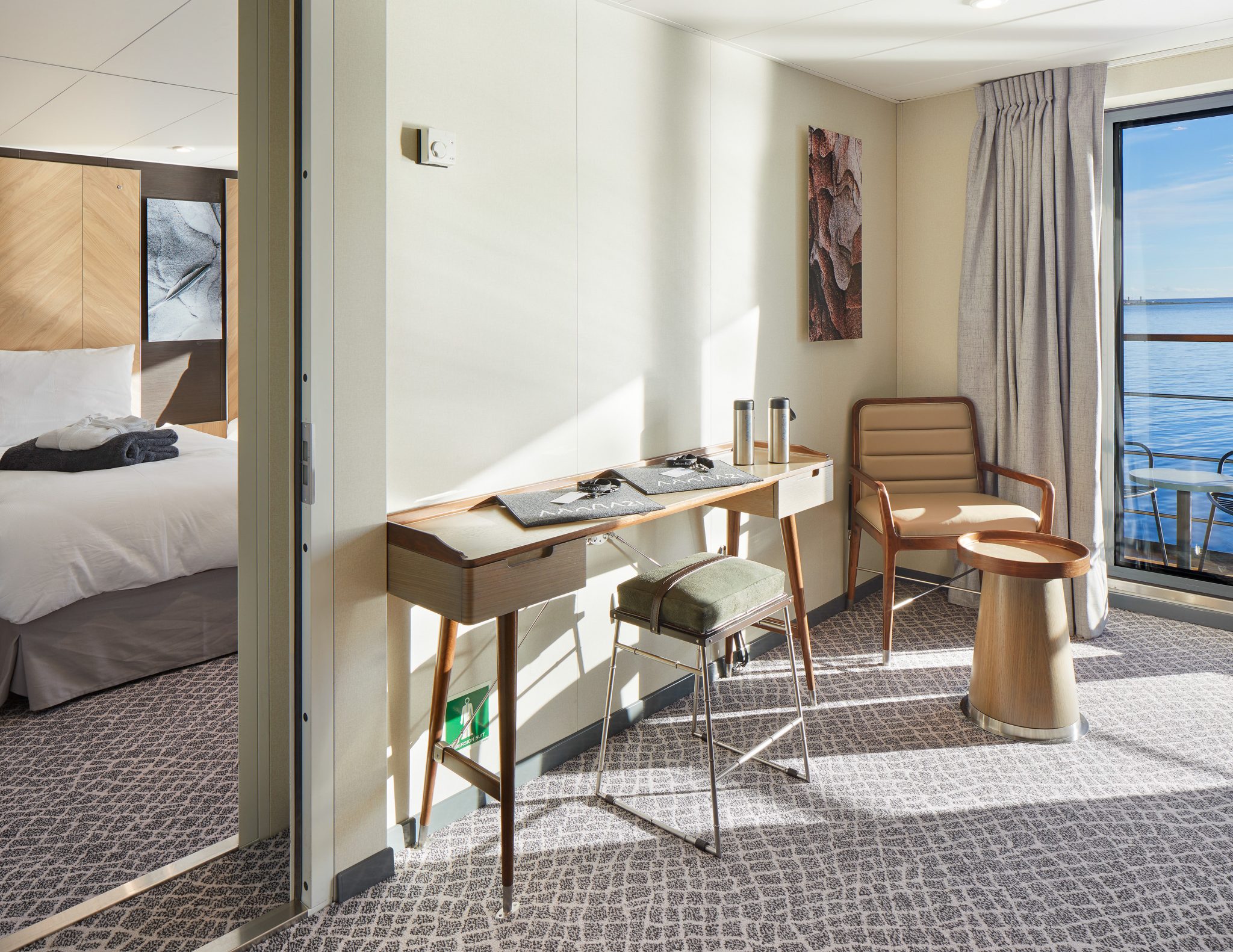 Two bedroom Deluxe Suite on Magellan Explorer showing a room with desk & chair and door leading to bedroom.