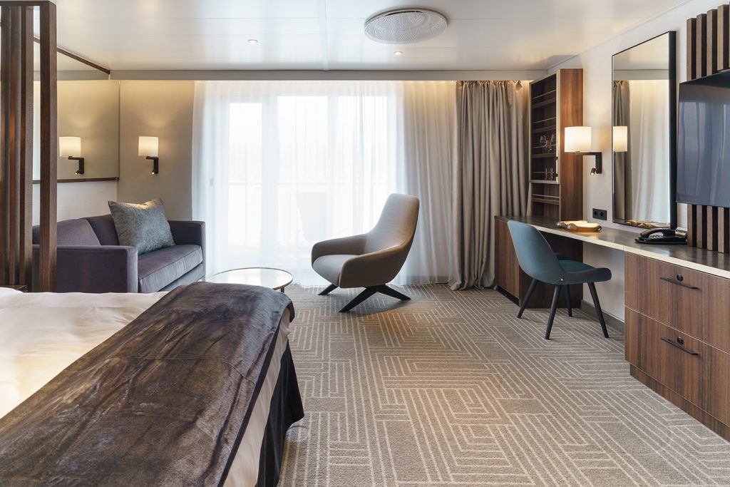 Deluxe Balcony Suite on Ultramarine showing double bed, desk and couch. 