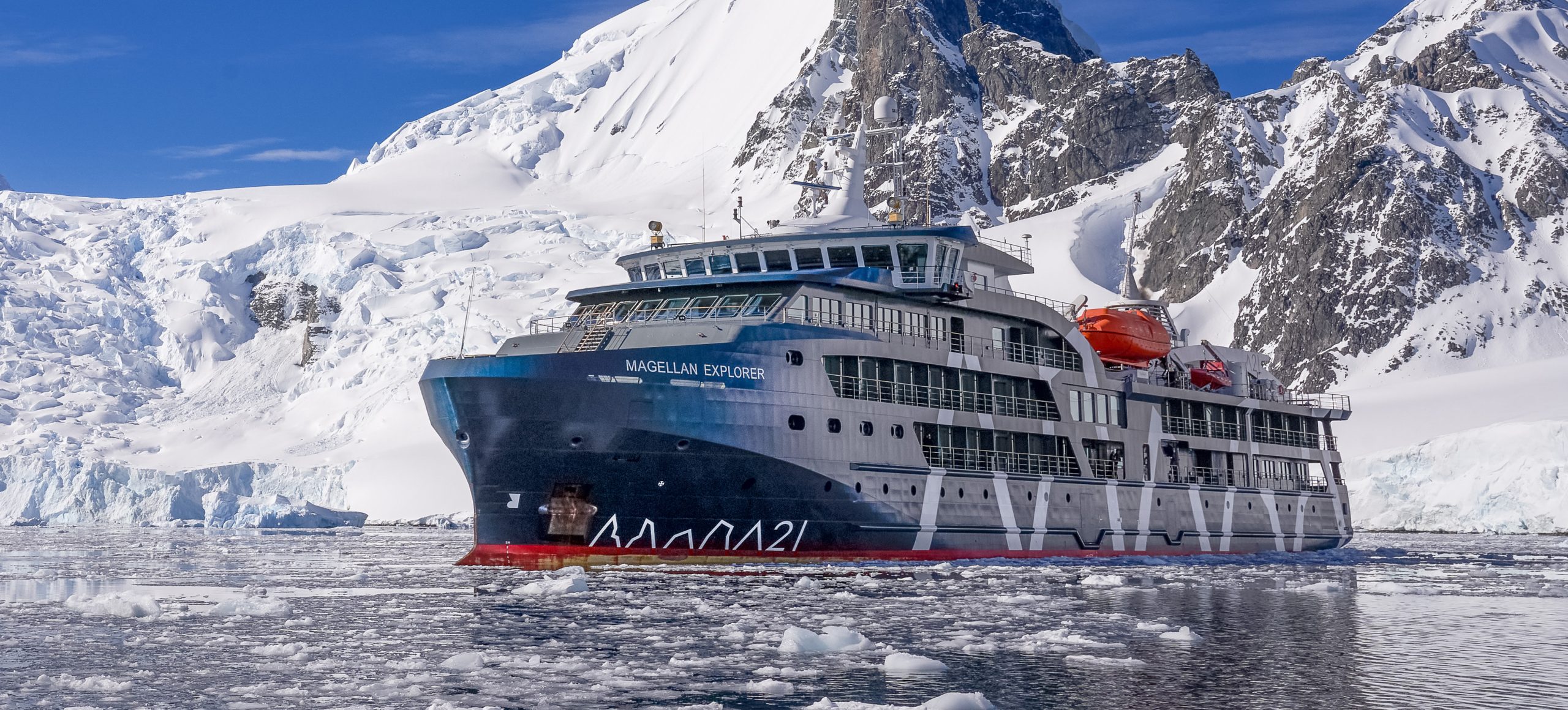 the ship Magellan Explorer in icy waters in Antarctica with mountains in background