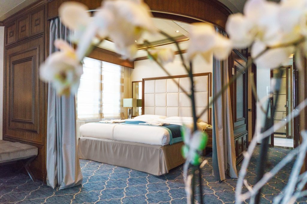 View of king bed bordered by white flowers in owner's suite on Sea Spirit. 