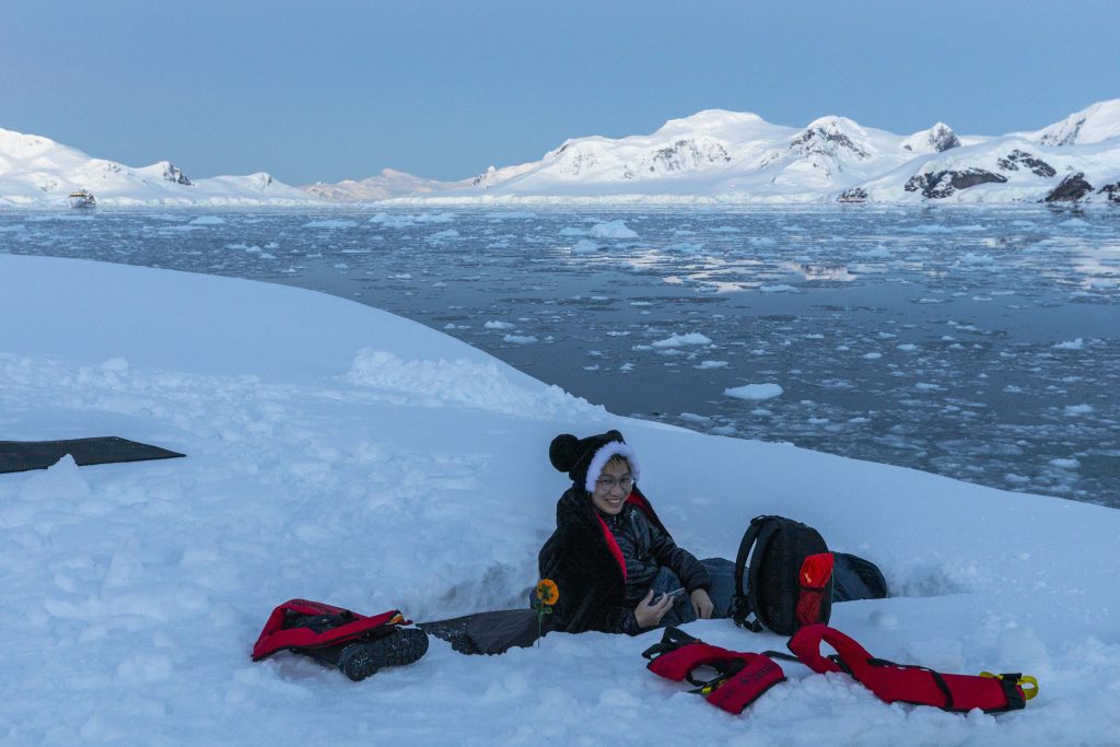 Guest sitting on sleeping bag in the snow in Antarctica