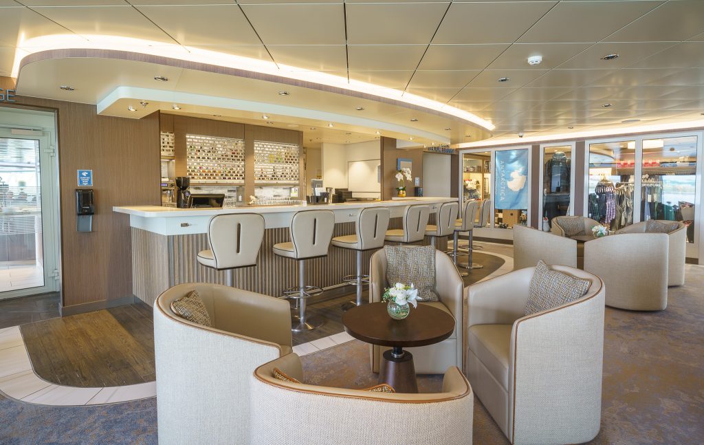 Bar with seven barstools and two small tables with 8 chairs in foreground. 