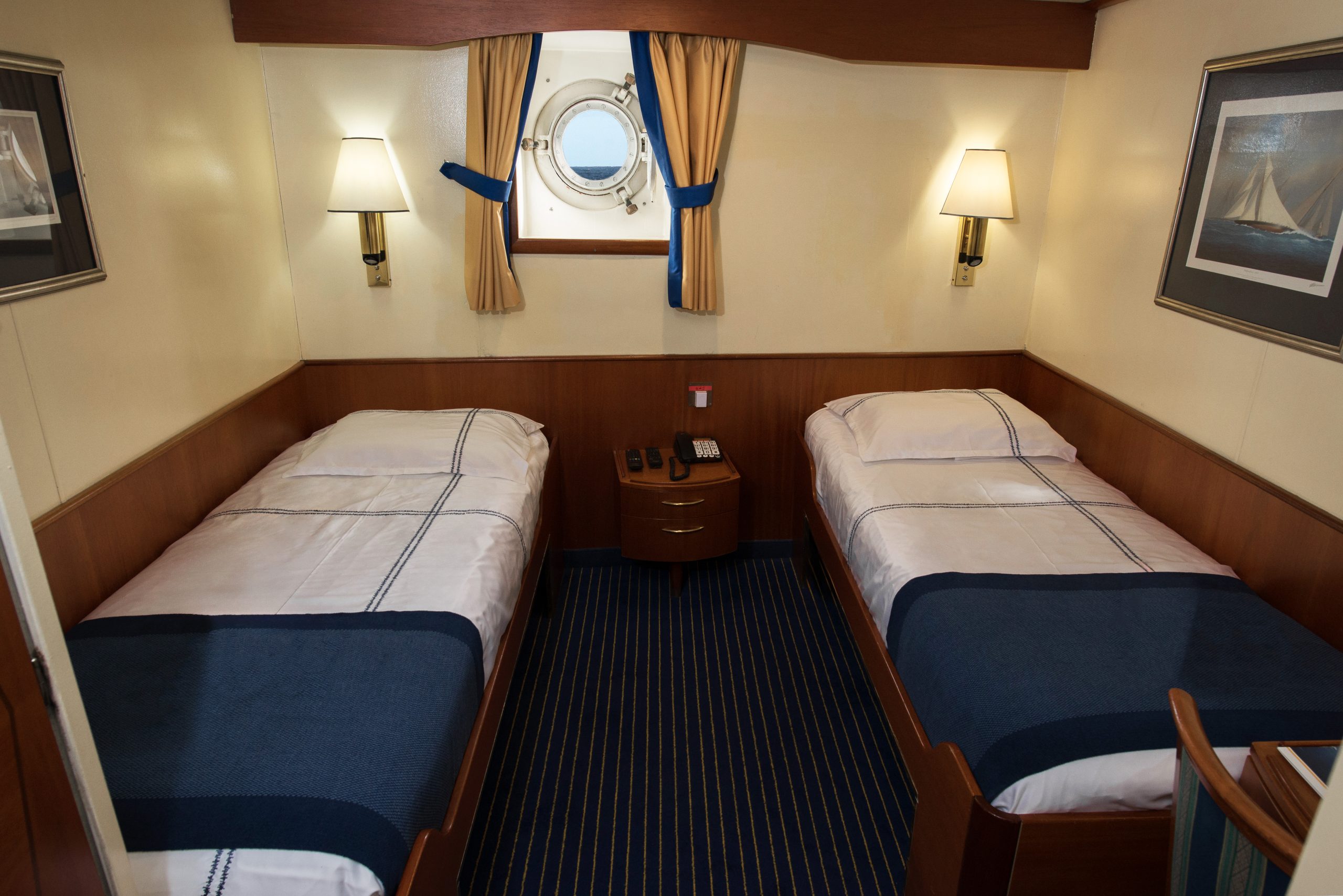 Cabin with 2 single beds and small porthole window.