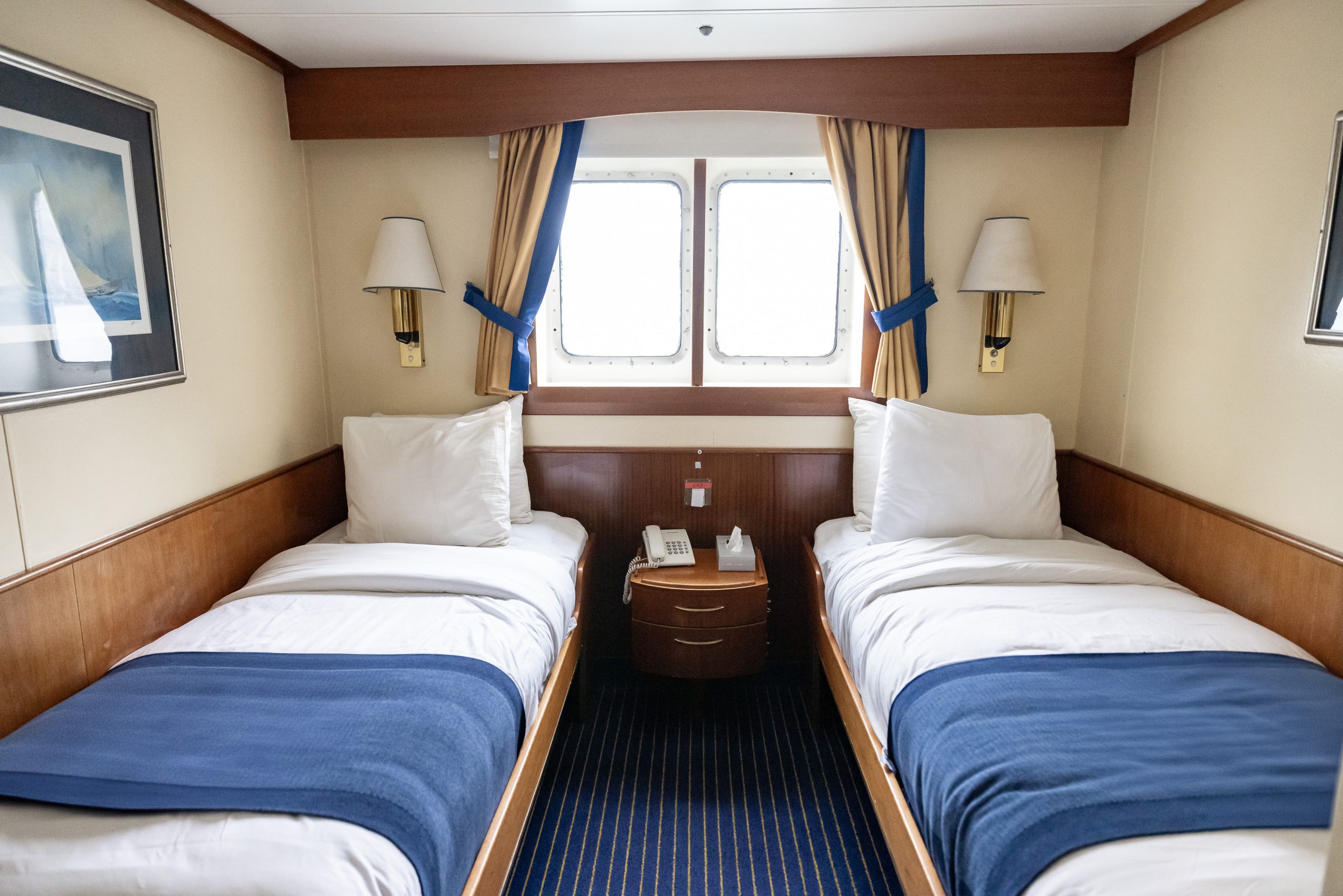 Interior of Main Deck Twin Window cabin on the ship Expedition showing 2 single beds and a window.