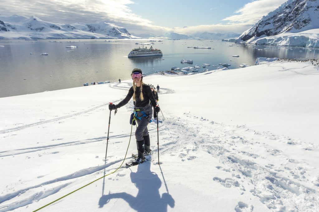 person snowshoeing in Antarctica with ocean and ship in background
