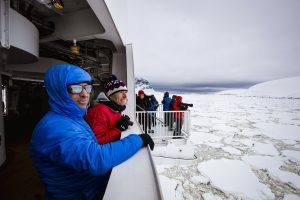 Guests looking out at sea ice while standing on the hydraulic platforms on the Greg Mortimer. 