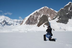 Photographer taking picture of glacier & mountains.