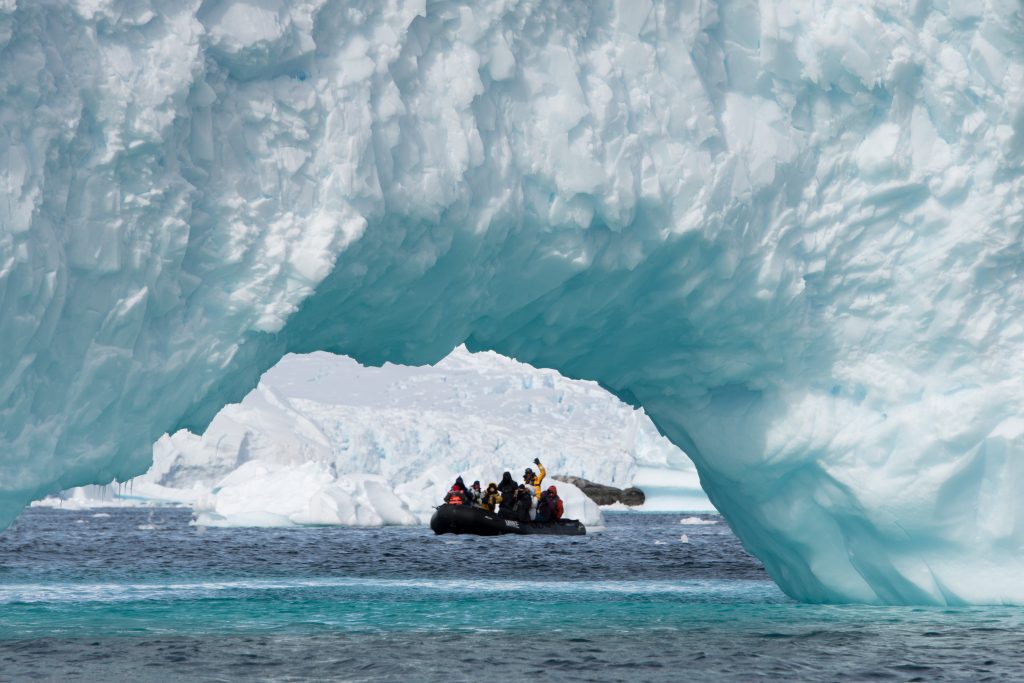 Zodiac cruising along large icebergs