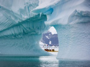 Kayakers in between two large icebergs in Antarctica. 