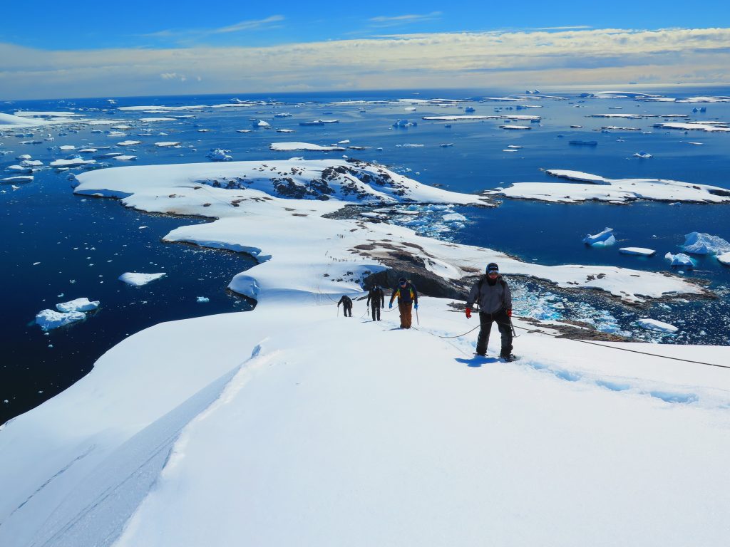 People hiking up mountain in snow.