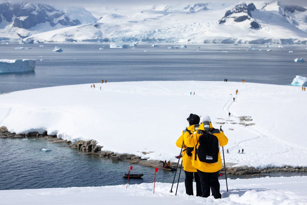 Passengers hiking down a snowy hill in Antarctica.