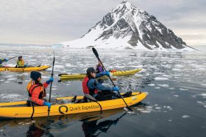 Kayakers paddling in icy waters.