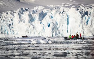 Zodiac cruising in front of a glacier face.