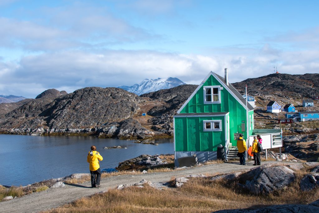 Guest standing outside small green house in Arctic community. 