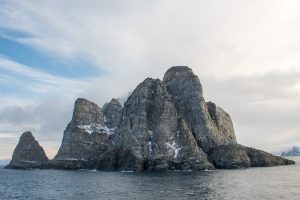 A steep rock cropping rising out of the sea.