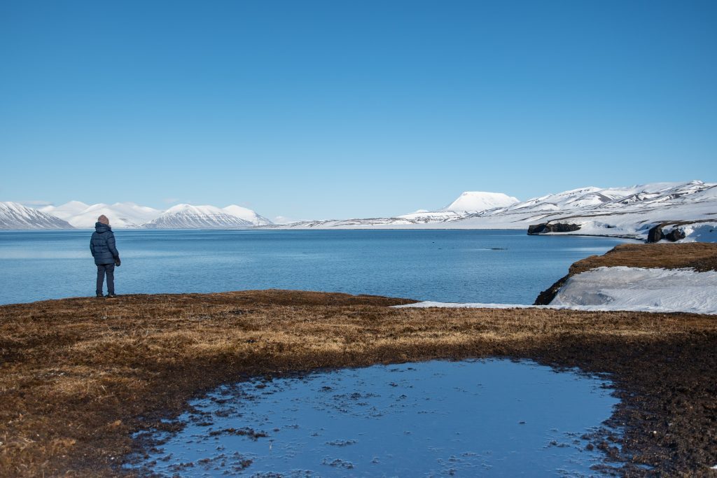 A guest gazing out at ocean & Arctic landscape in Svalbard.