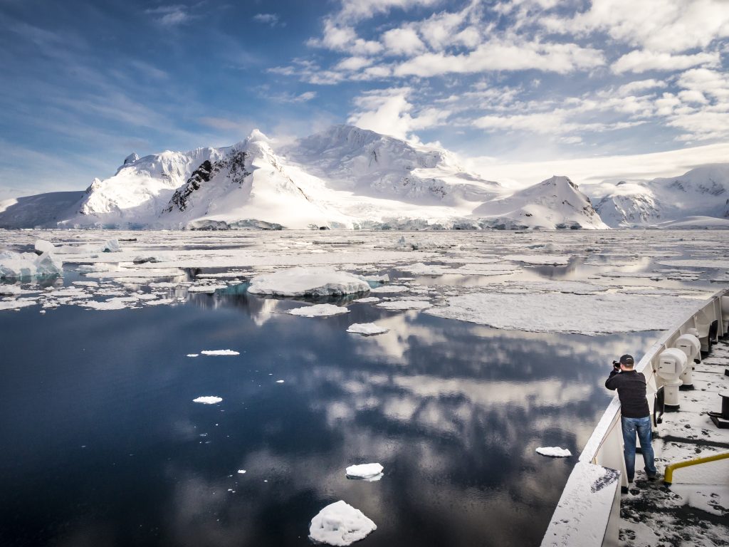 Guest on bow of ship looking at Antarctic landscape. 