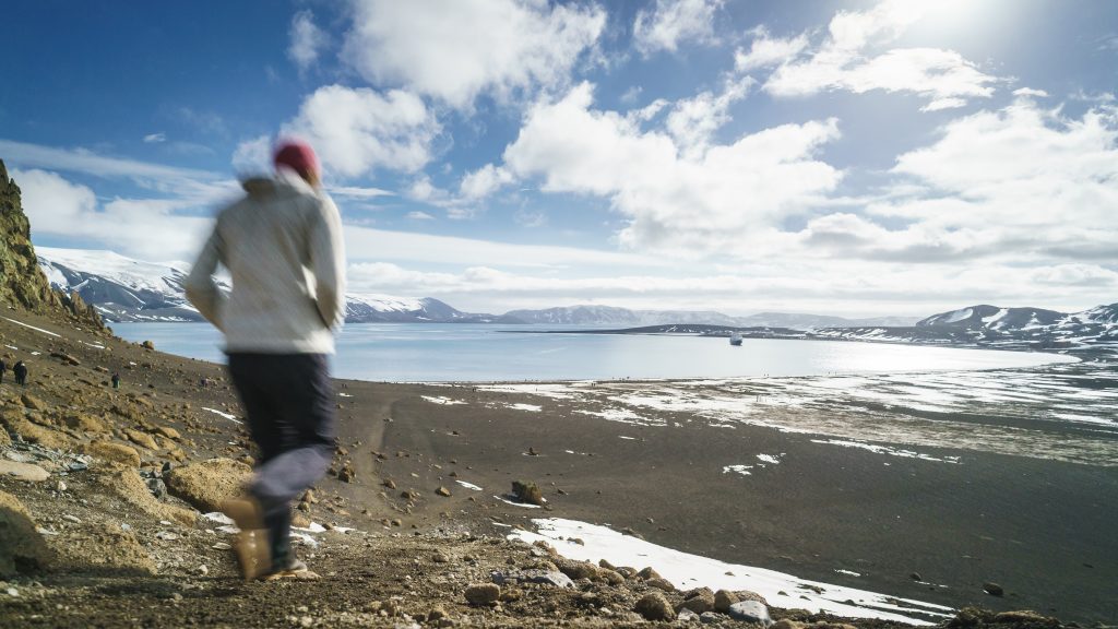 Guest hiking down hillside toward ocean. 
