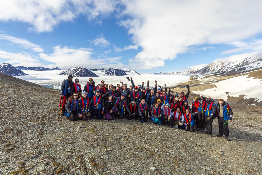 Group of guests with large glacier in background. 