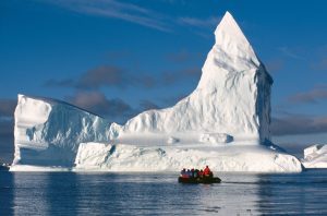 Guest in zodiac on the water in front of massive iceberg.