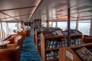 National Geographic Explorer Library showing bookshelves, chairs and large windows with sea view.