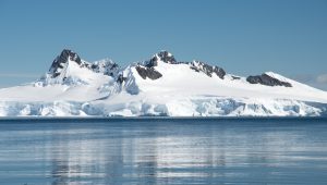 Snow covered mountains rising out of the water.