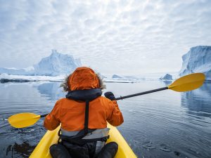 Kayaker paddling towards icebergs in Antarctica.