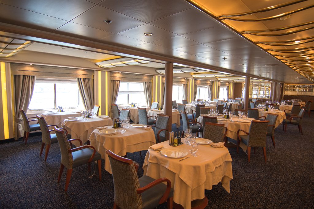 The restaurant with circular tables, white table clothes and chairs on Silver Cloud. 