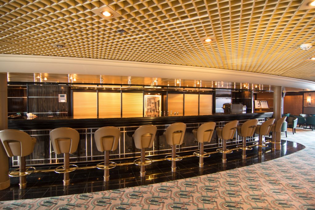 Large bar with golden lights and 10 barstools on Silver Cloud. 