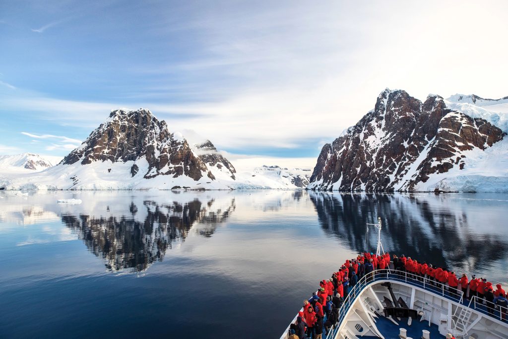 Passengers on the bow of Silver Cloud with stunning mountains in background.