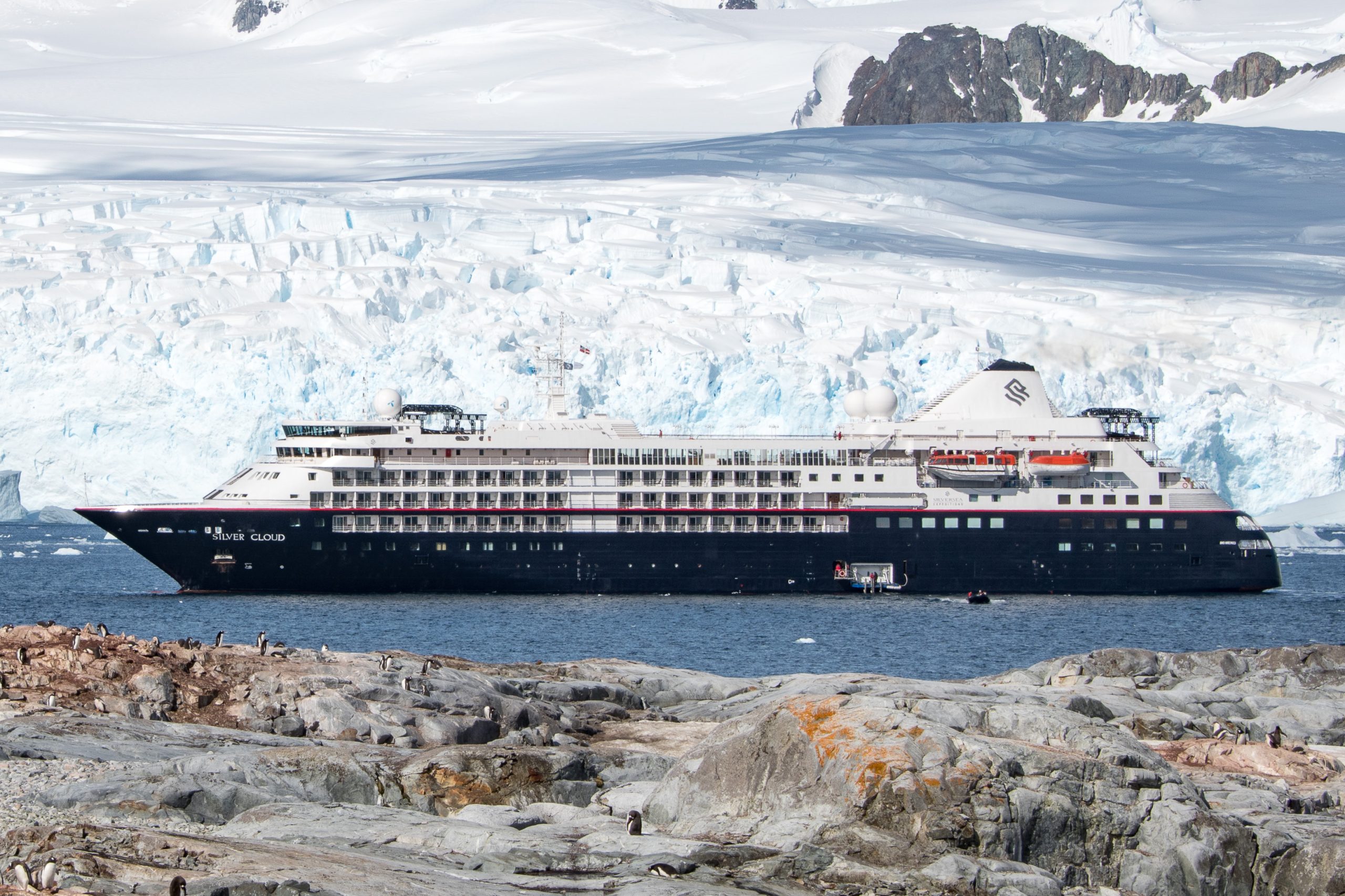 The ship Silver Cloud on the water in Antarctica with glacier in the background.