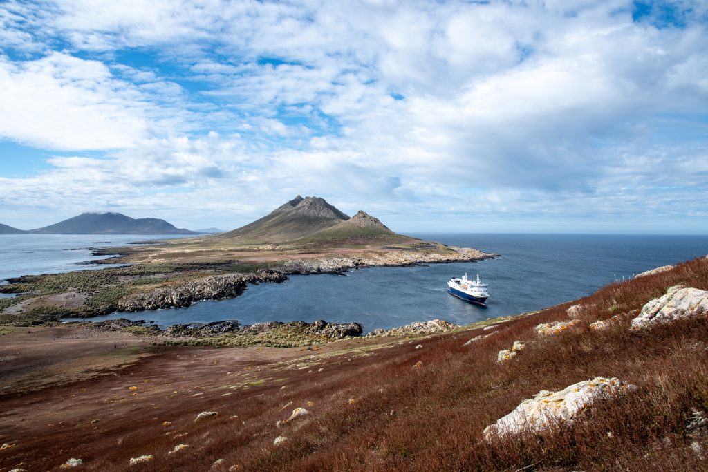 The ship National Geographic Explorer anchored in a bay.