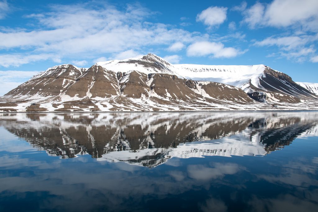 Snowy mountains with reflection in calm water.
