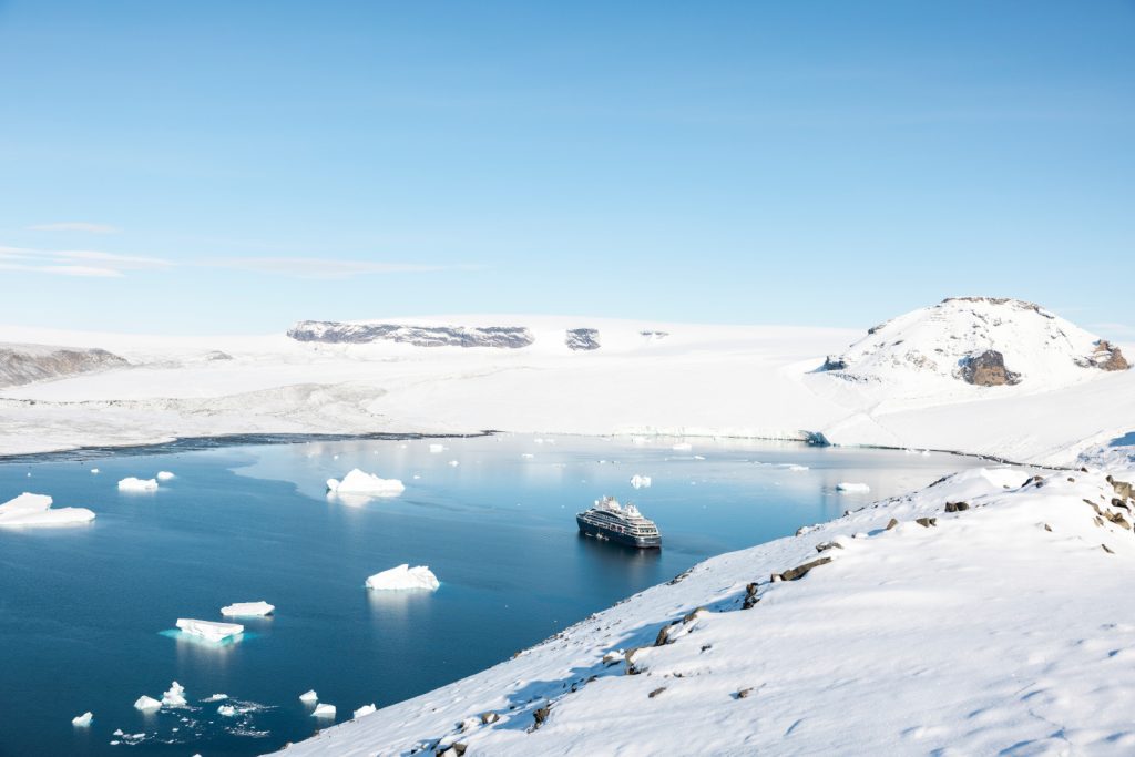 The ship Le Commandant Charcot anchored in a snowy bay. 