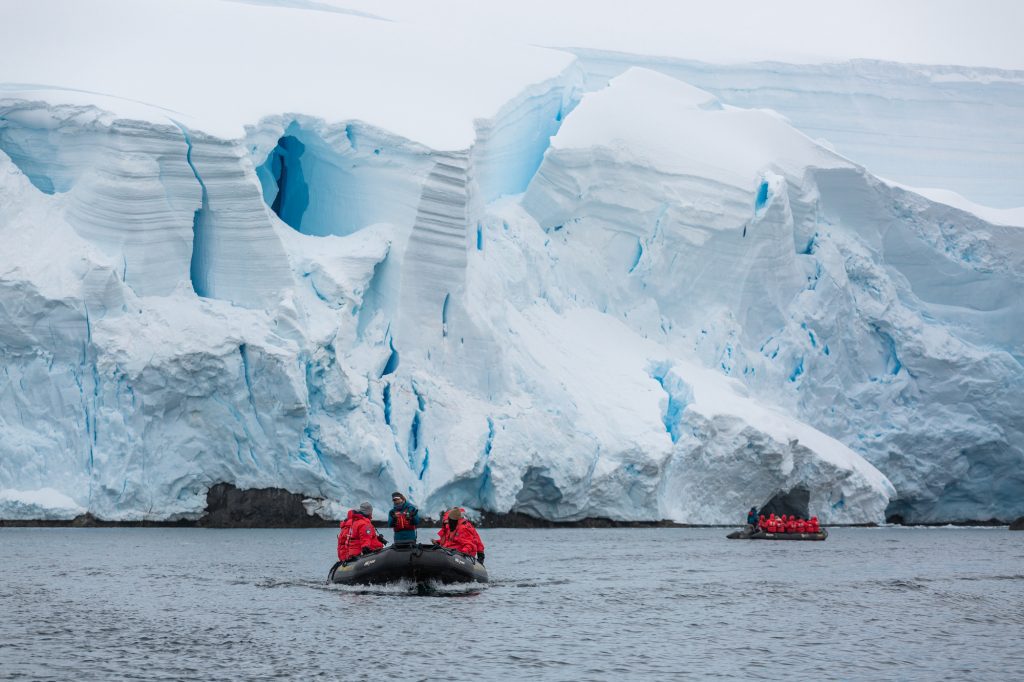 Two zodiacs cruising in front of glacier. 