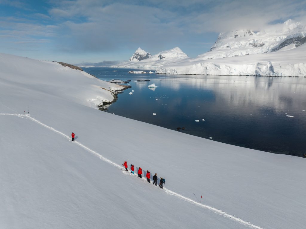 Guests hiking in the snow close to the shoreline. 