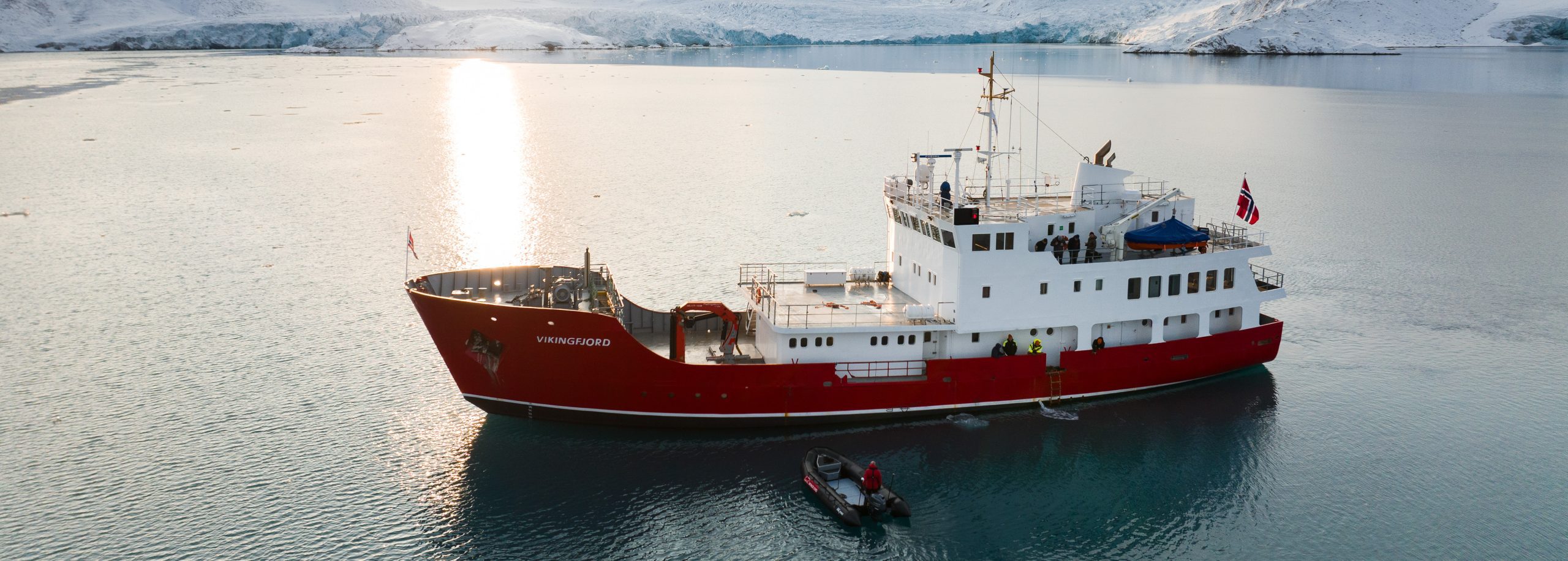 MV Vikingfjord in Svalbard with Zodiac and sun in background Secret Atlas