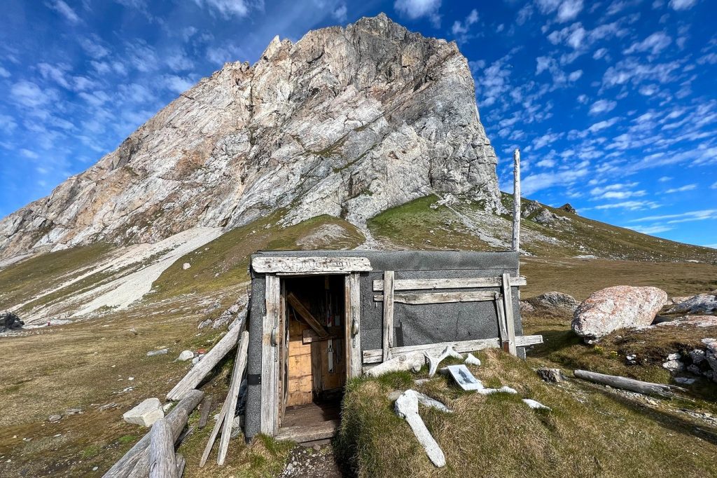 A trapping hut near the base of a rocky peak. 