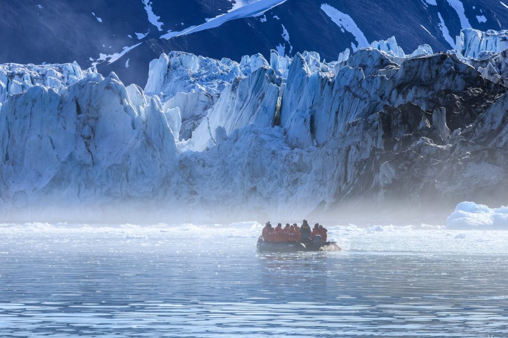 A zodiac full of passengers near glacier.