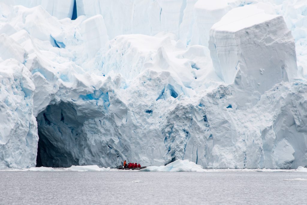 zodiac cruising in Antarctica with large glacier face in background