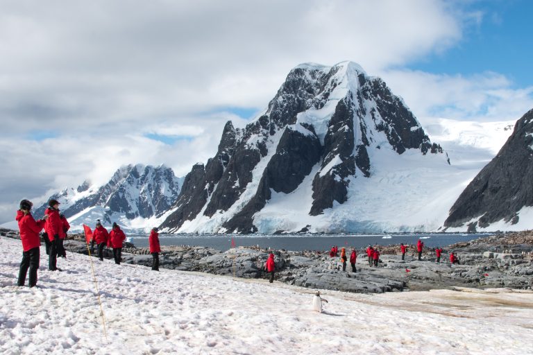 Guests hiking at Petermann Island with mountains in background