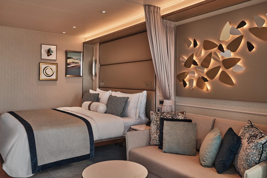 King bed with adjacent sitting area with couch in veranda suite on Silver Endeavour. 