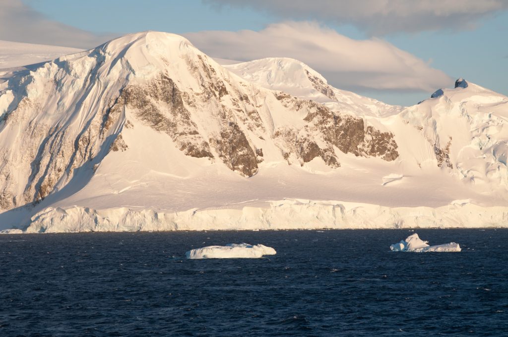 Snow covered mountain with soft light & iceberg in the foreground. 