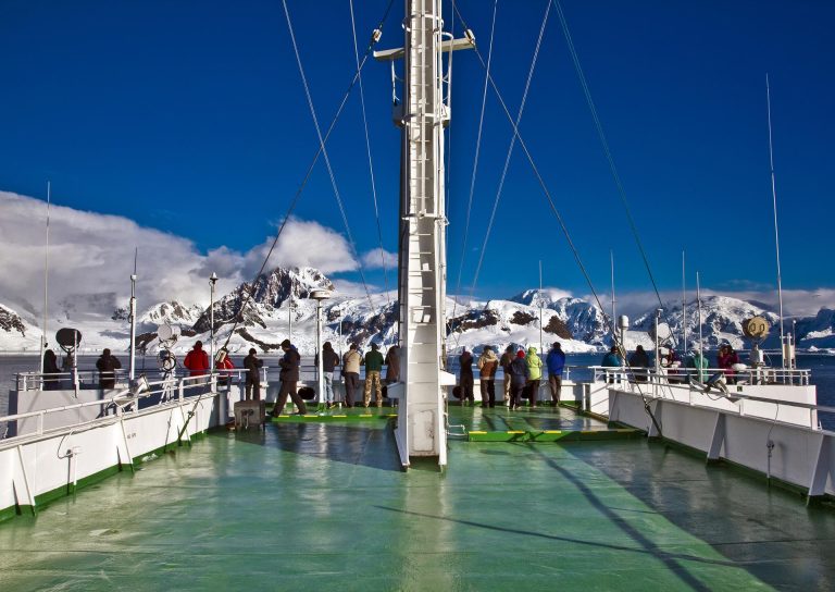 Expedition ship deck space with passengers observing beautiful mountain views