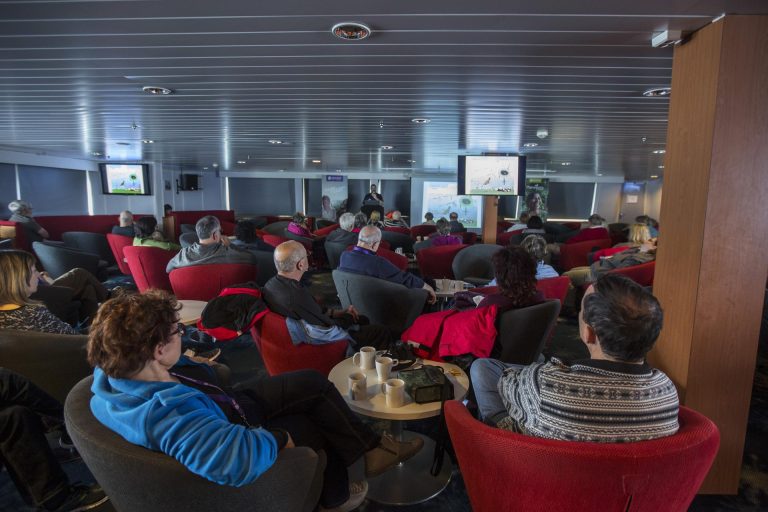 Presentation Lounge on the Expedition ship with passengers seated in chairs, presenter and screen