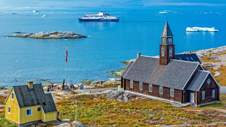 Ilulissat town in West Greenland with church and ship Ocean Endeavour in the background