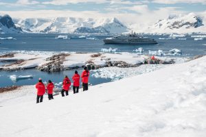 Guests standing in red jackets on snowy slope in Antarctica.