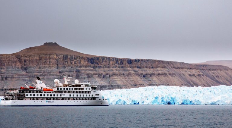 The Greg Mortimer ship cruising in the Northwest Passage with large glacier in the background